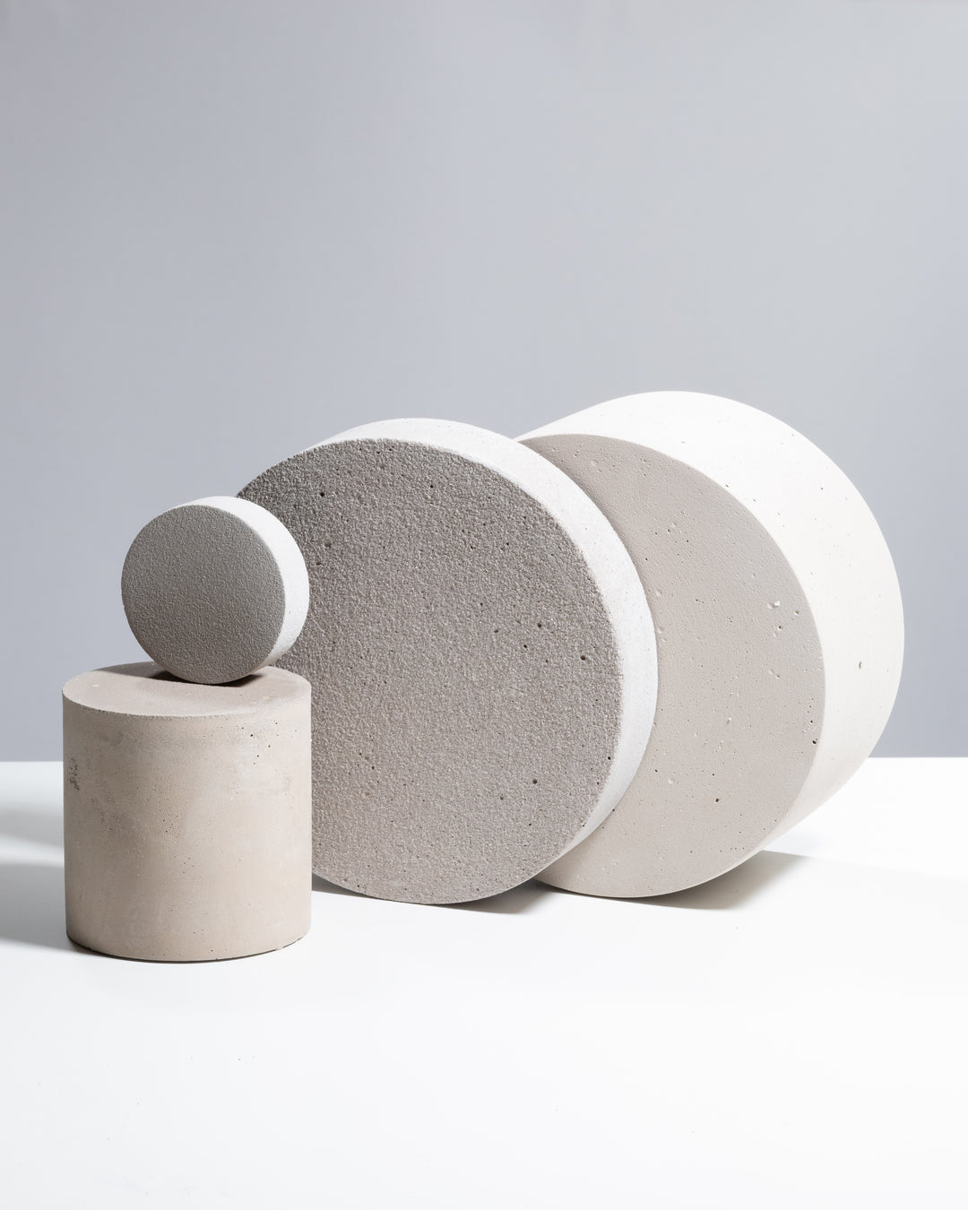 Three cylindrical concrete objects of varying sizes on a light gray background