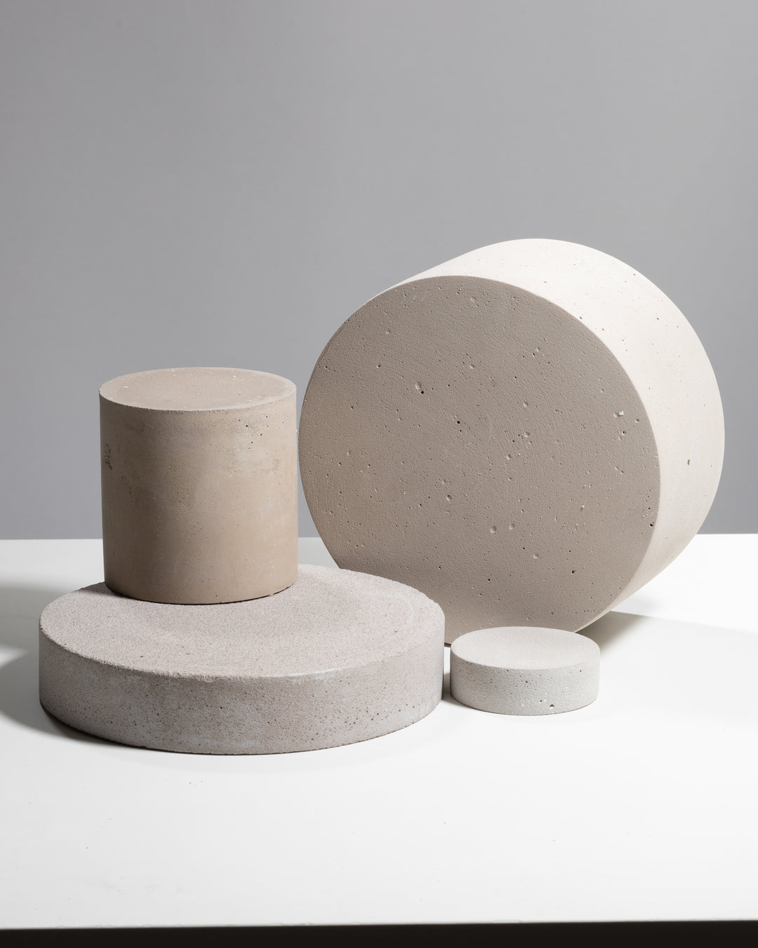 Set of four neutral concrete cylinder photography props in different sizes for product styling