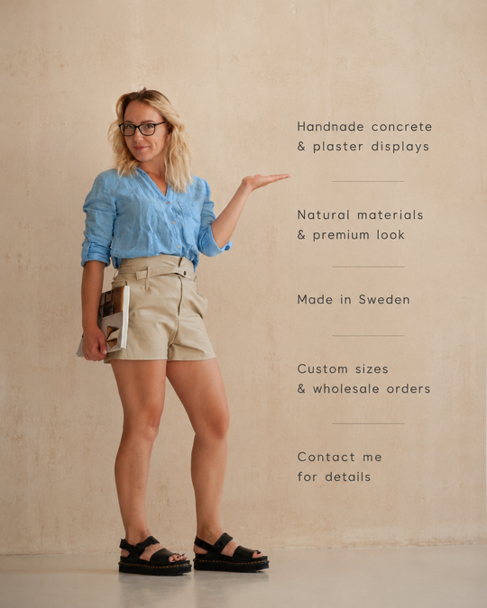 Woman in a blue shirt and beige shorts holding a book, with text about handmade concrete and plaster displays.