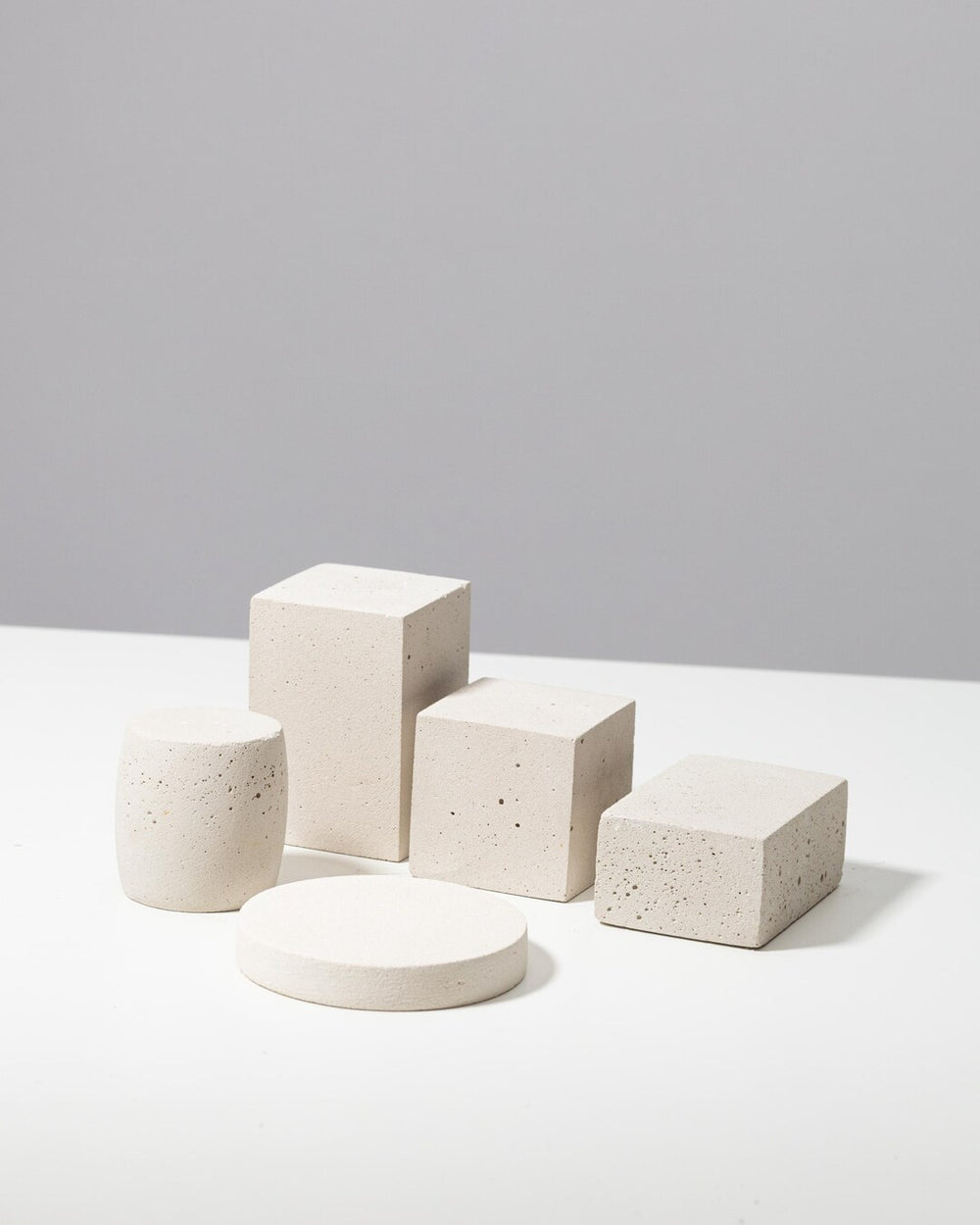 Set of five off white display props: tall block, cube, low block, cylinder and round disc