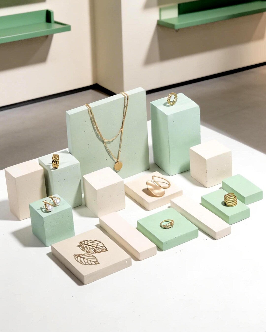 Gold jewelry displayed on mint green and ivory modular concrete blocks