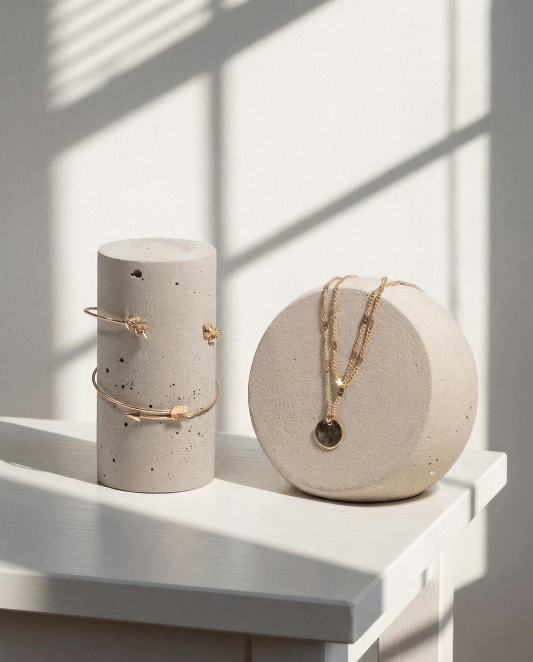 Stone-look mineral jewelry display duo in warm beige styled with gold jewelry