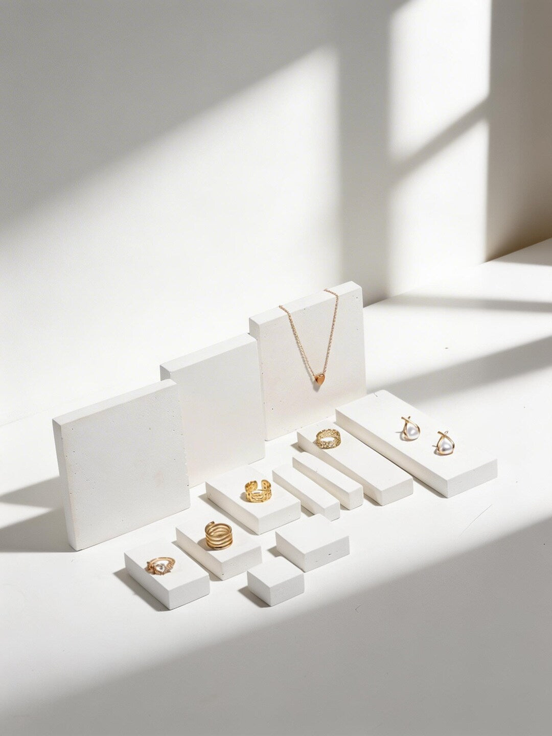 Gold jewelry styled on white rectangular display blocks and bars