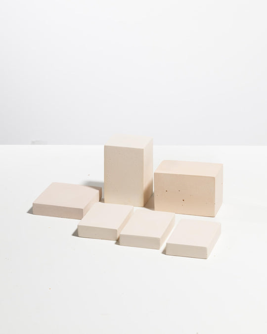 Set of six light beige rectangular display blocks of varying heights with matte finish