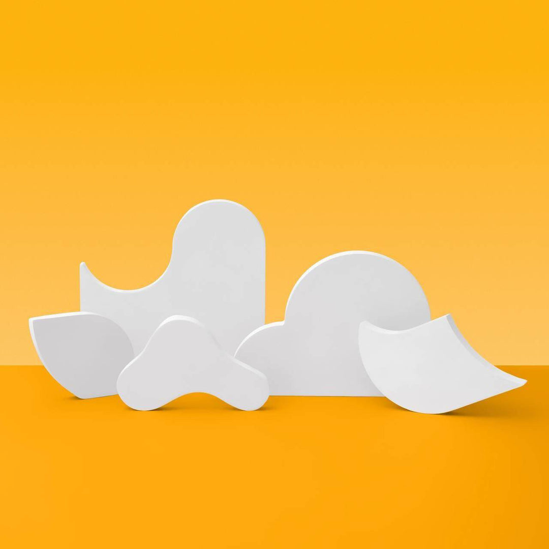 Editorial product photo of the four-piece Dune sculptural display stand set on a warm yellow background, handmade gypsum risers for jewelry and beauty brands