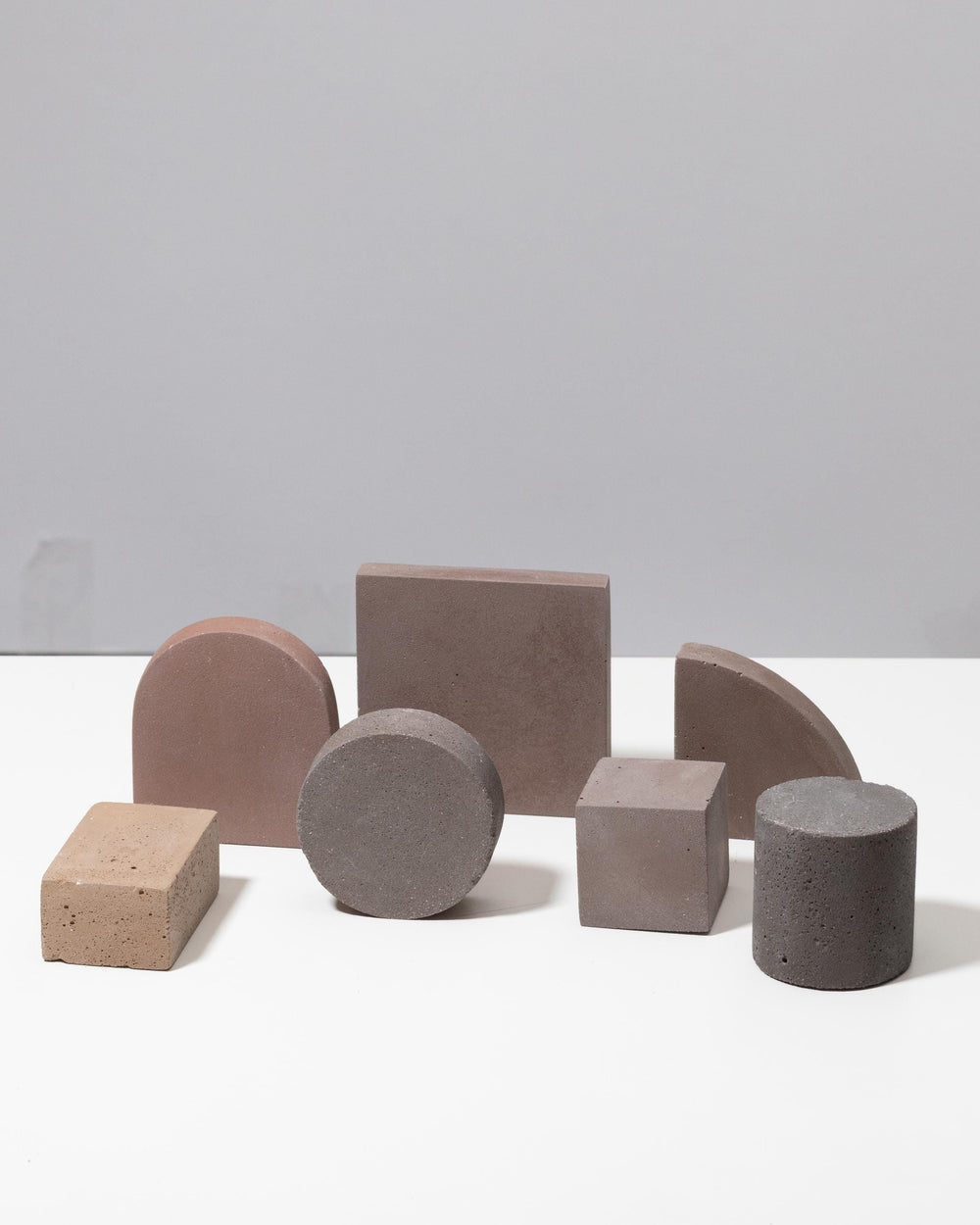 Assorted geometric display shapes: cube, cylinder, half circle and blocks in warm tones