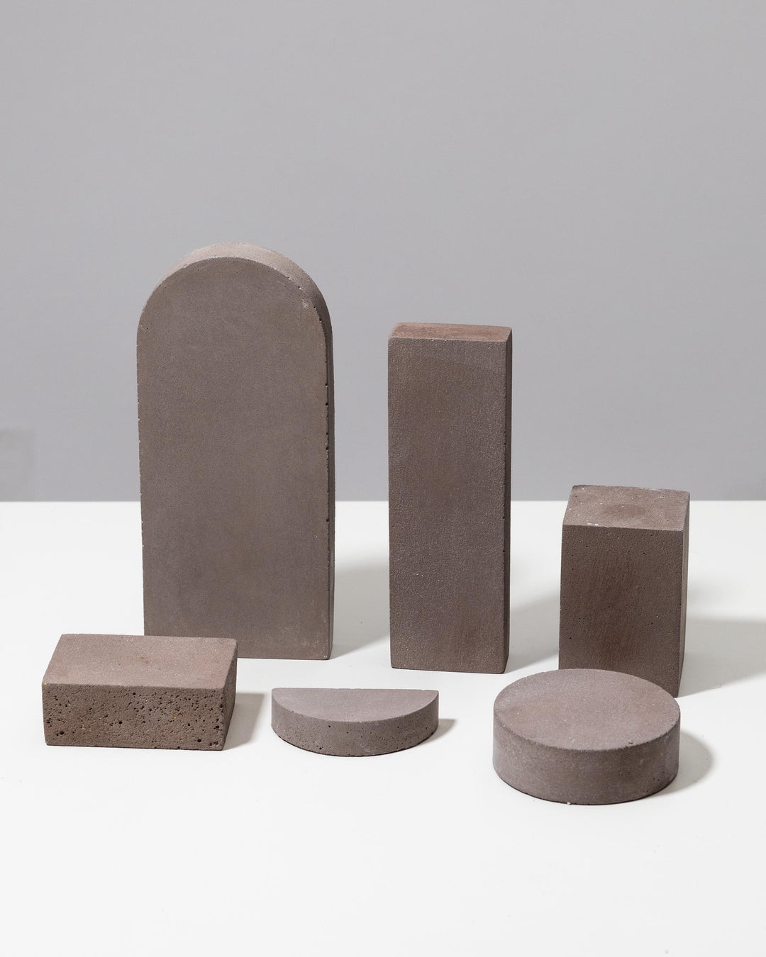 Set of five grey geometric display shapes: blocks, cube, half circle and cylinder