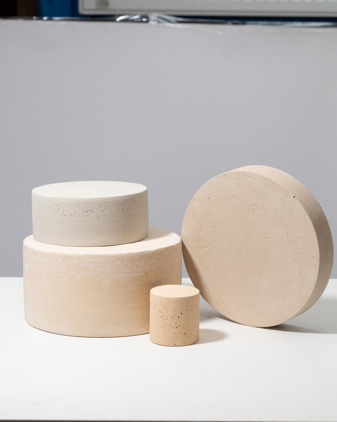 Four round plaster pedestals in beige and off white stacked for styling