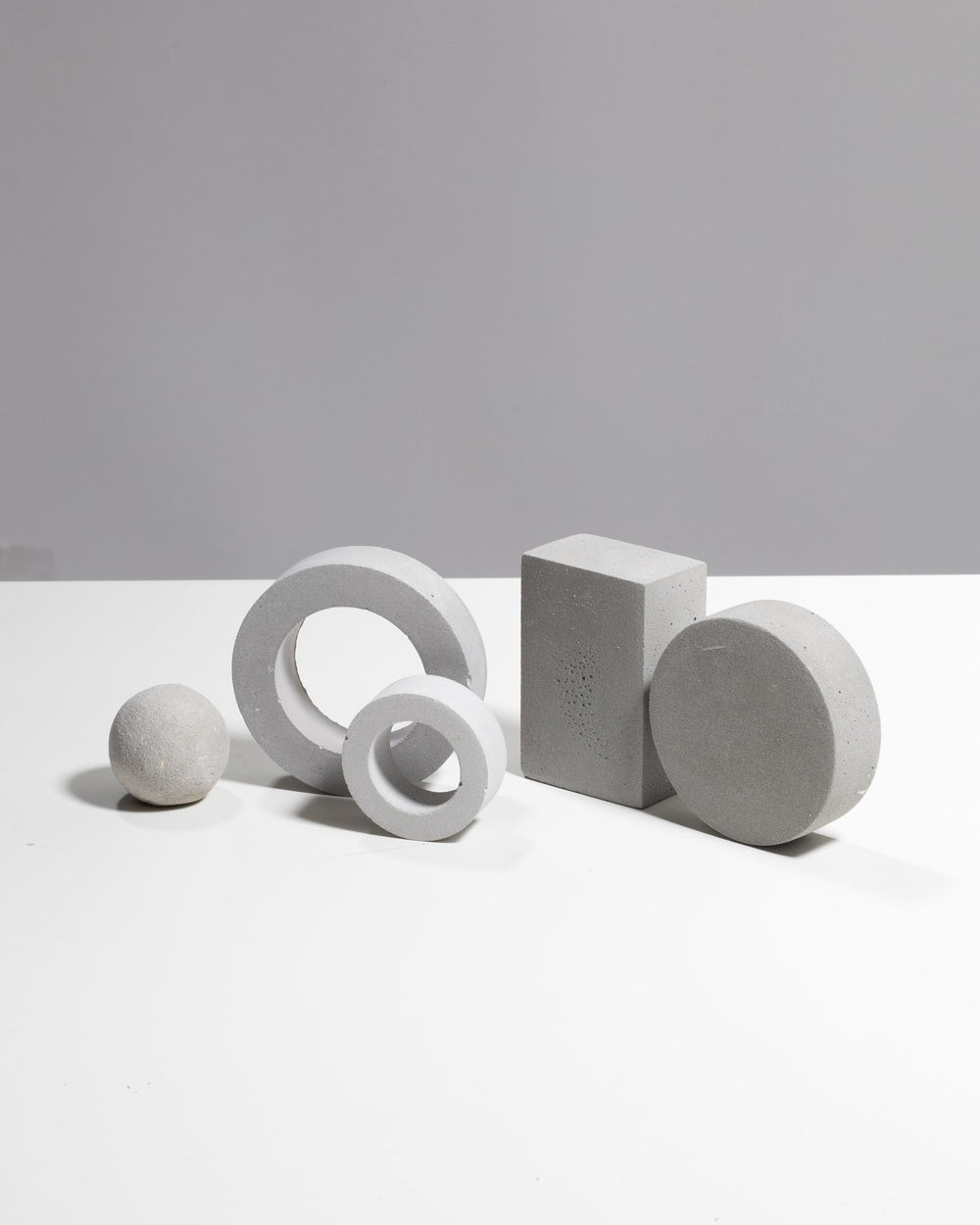 Five geometric plaster shapes in light grey arranged for styling