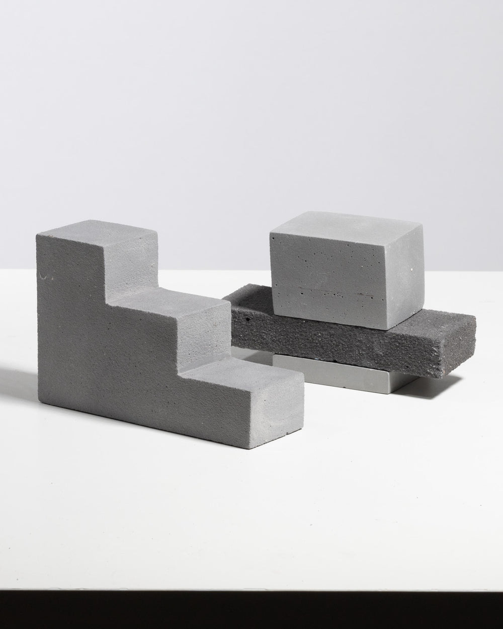 Grey plaster step riser with stacked rectangular display blocks, matte mineral finish