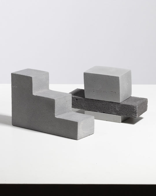 Grey plaster step riser with stacked rectangular display blocks, matte mineral finish