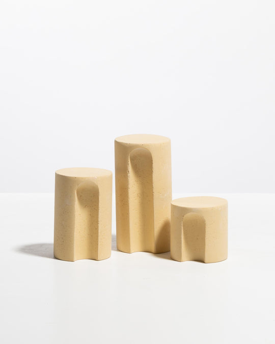 Three pale yellow arch cylinder display pedestals in graduated heights