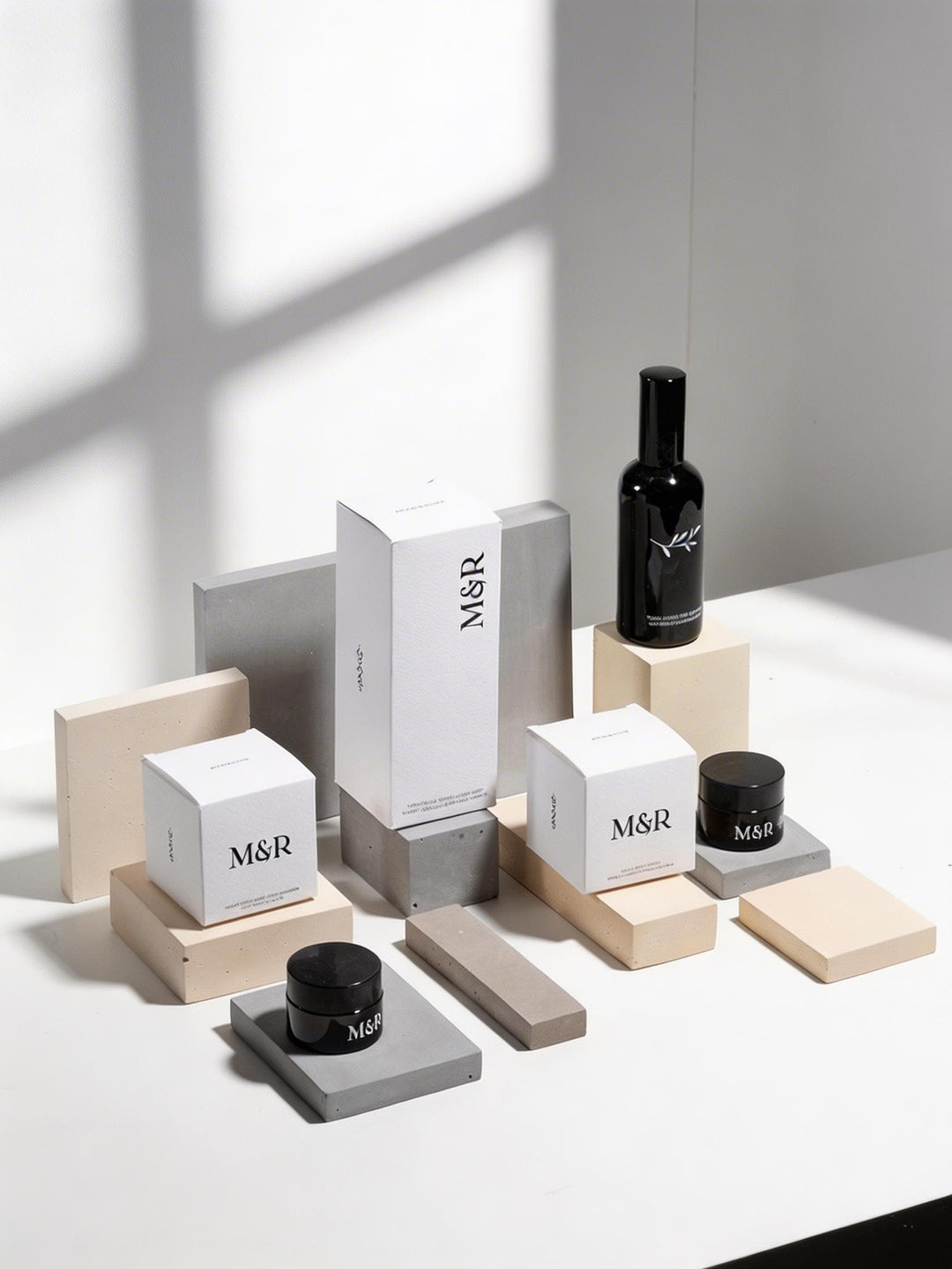 Neutral display risers styled with M and R skincare packaging on concrete and beige blocks