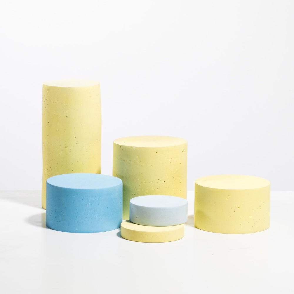 Set of six cylindrical display pedestals in pastel yellow and light blue with matte finish