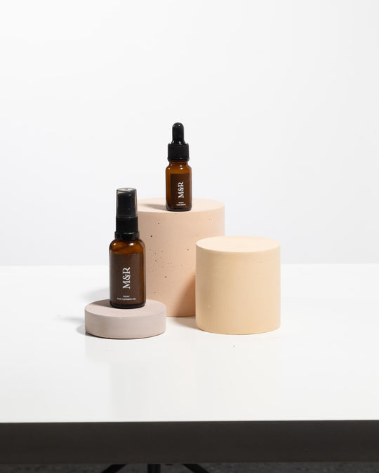 Concrete exhibition plinths in varying heights styled with amber glass cosmetic bottles