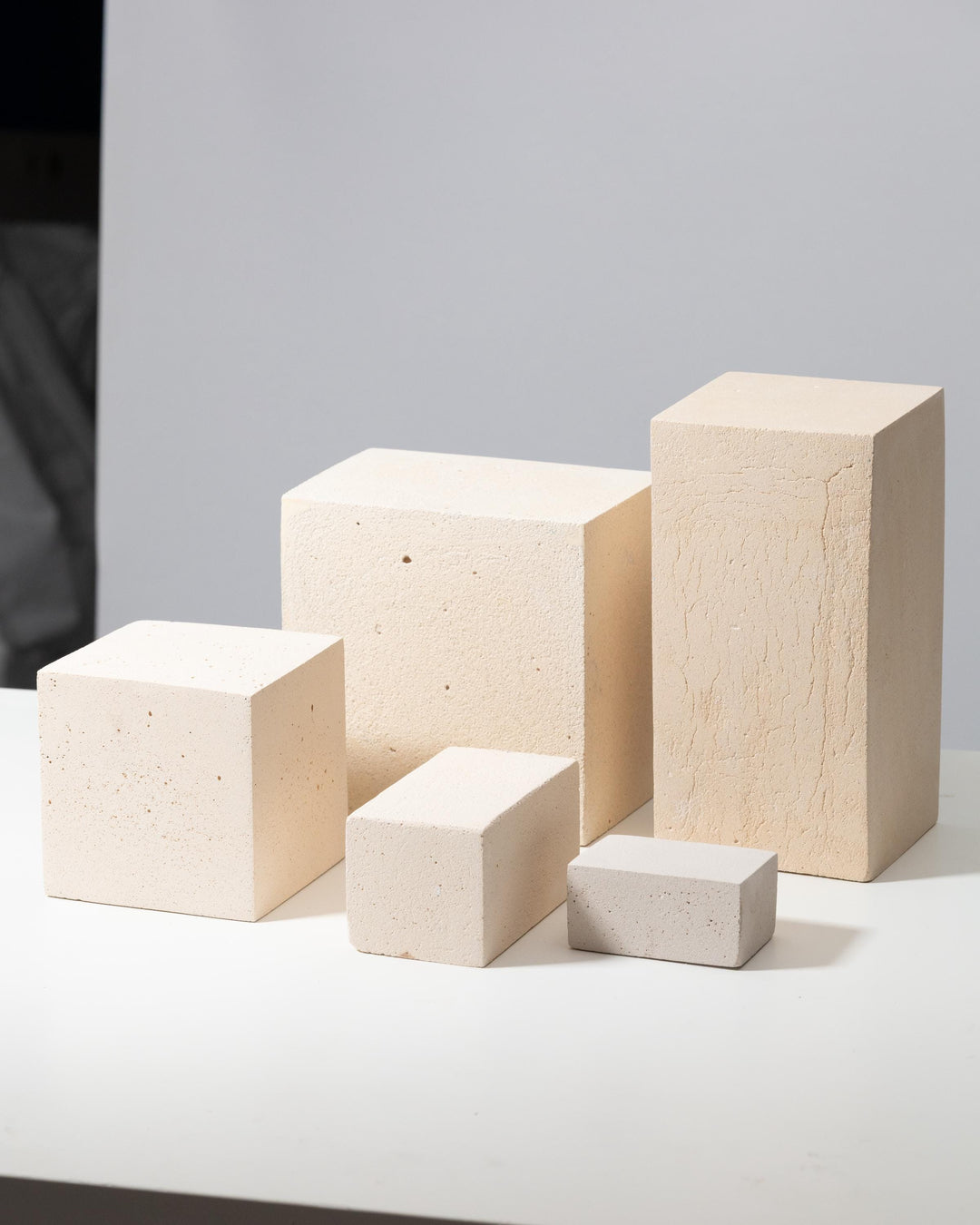 Five off-white concrete display blocks with porous matte texture