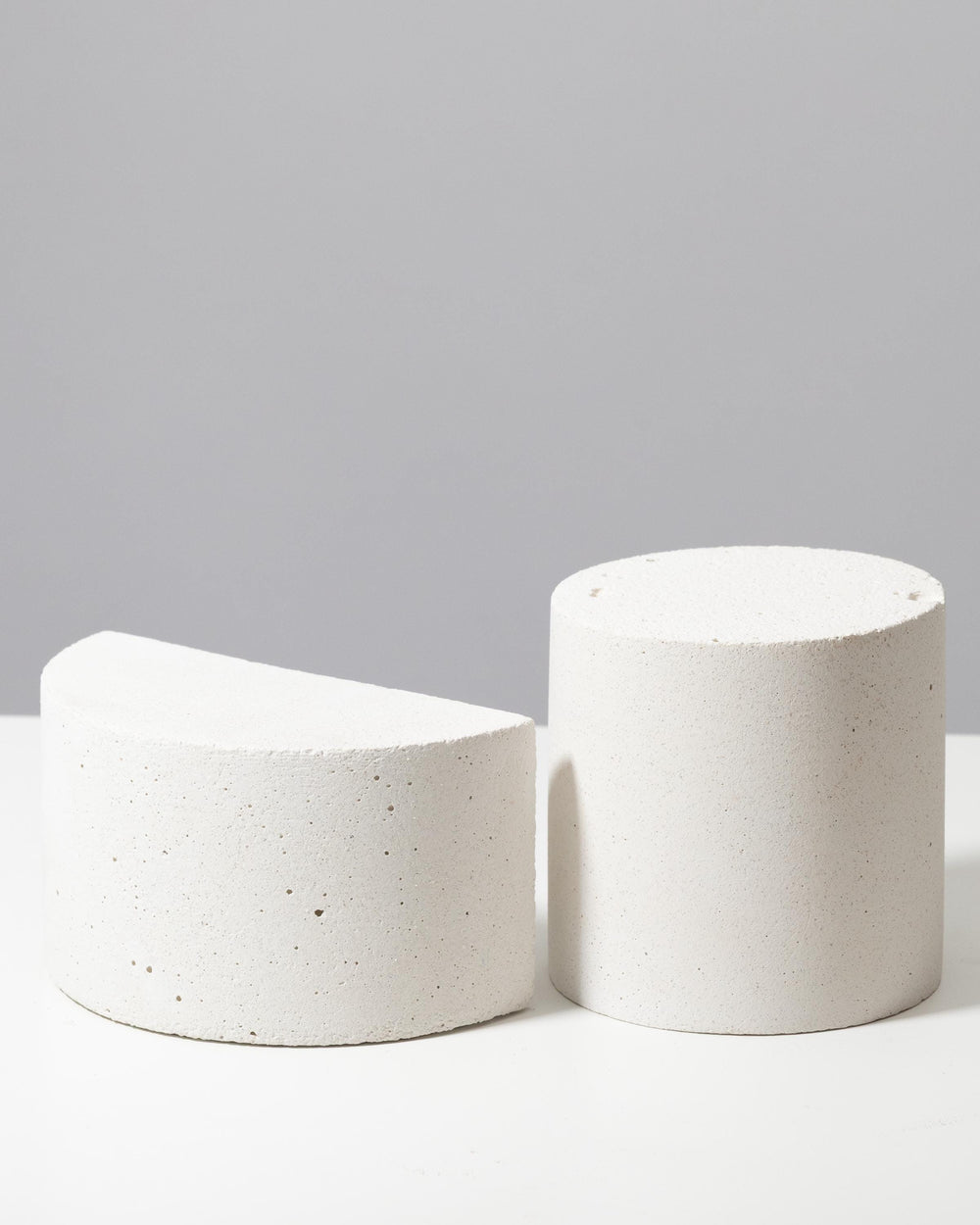 Textured white cylinder and half cylinder display pedestals with porous mineral surface