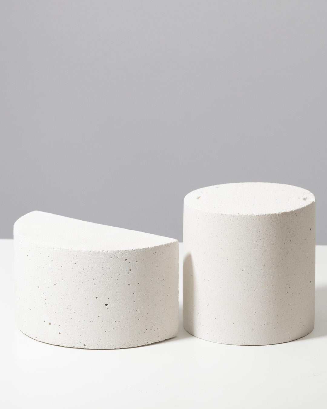 Textured white cylinder and half cylinder display pedestals with porous mineral surface