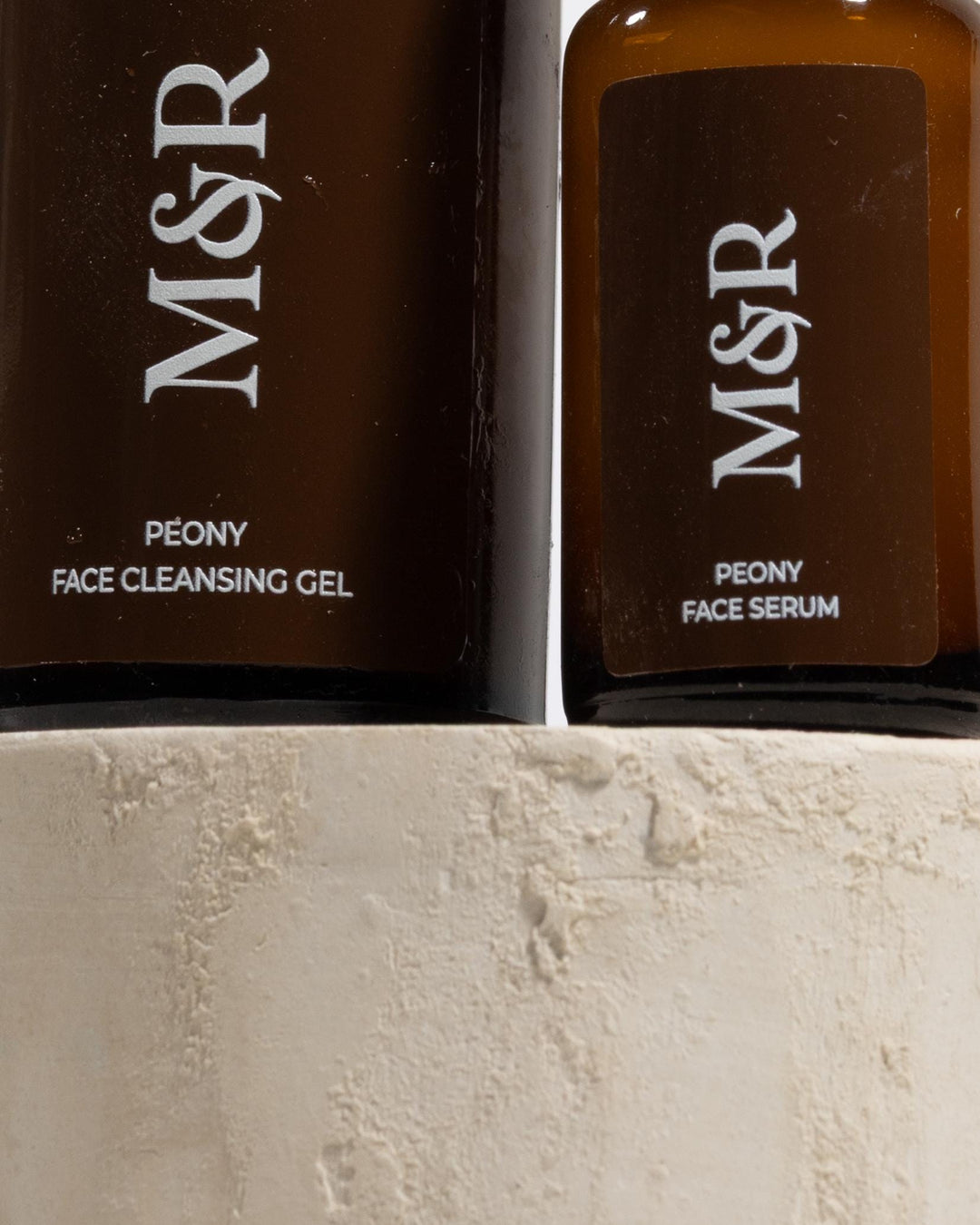 Skincare bottles styled on beige cylinder display pedestals