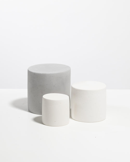 Three cylinder display pedestals in light grey and white with speckled texture