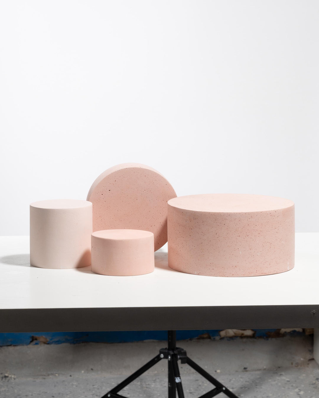 Four cylindrical display pedestals in pale pink with tall vertical disc